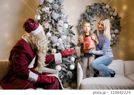 Santa claus watching mother and son decorating christmas tree Santa claus watching mother and son decorating christmas tree 120682224