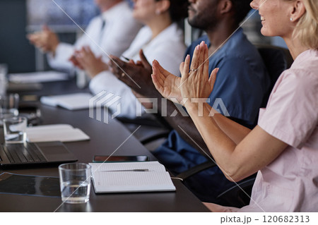 Cropped shot of smiling female clinician clapping hands supporting colleagues presentation while attending working meeting in medical boardroom, copy space Cropped shot of smiling female clinician clapping hands supporting colleagues presentation while attending working meeting in medical boardroom, copy space 120682313