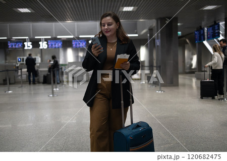 Portrait of positive cheerful traveler woman hold ticket ready enjoy voyage tour passenger walk in airport terminal to boarding gate. Attractive beautiful female tourist excited to go travel abroad by 120682475