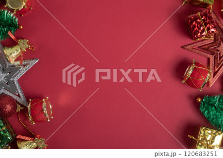 Festive Christmas decorations on bright red background, gifts, baubles, mini tree, stars, bells and drum ornaments 120683251
