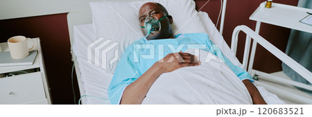 African American elderly man lying in hospital bed with oxygen mask, appearing resting African American elderly man lying in hospital bed with oxygen mask, appearing resting 120683521