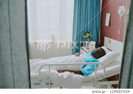 African American patient resting in hospital bed receiving medical care surrounded by medical equipment and soothing decor creating a calm atmosphere 120683584