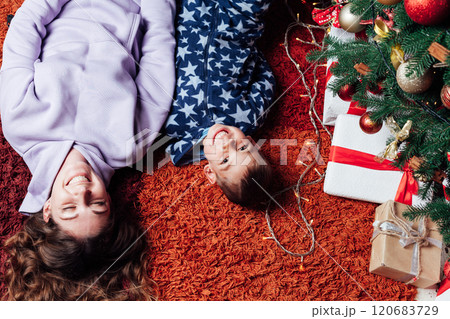 Mother and son at christmas tree with gifts lights garland decorated Mother and son at christmas tree with gifts lights garland decorated 120683729