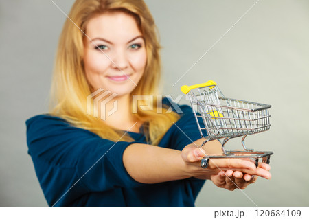 Happy woman holding small tiny shopping cart Happy woman holding small tiny shopping cart 120684109