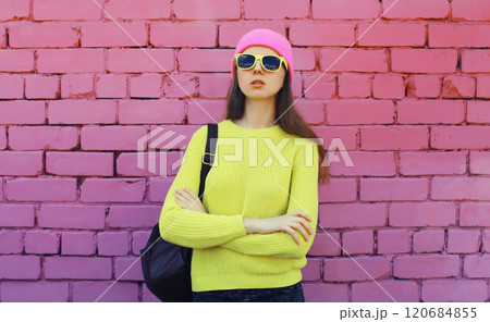 Stylish young teenager girl posing in vivid yellow colorful clothes on pink brick wall background 120684855