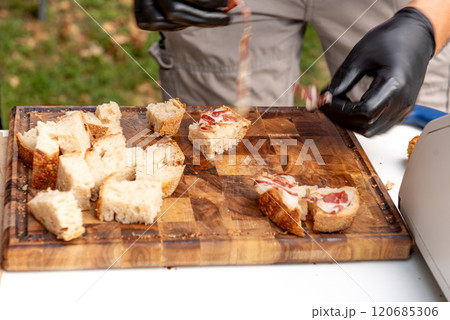 cutting bread and ham on wooden cutting board for tasting 120685306