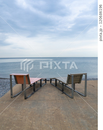 Benches for lying by the sea. Sun loungers in the park against the background of the sea. Benches for lying by the sea. Sun loungers in the park against the background of the sea. 120686196