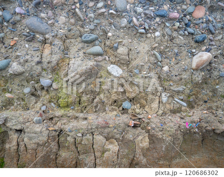 Layers of earth on a beach made of pebbles. Soil cut. Cobblestones and earth. After the excavator. 120686302