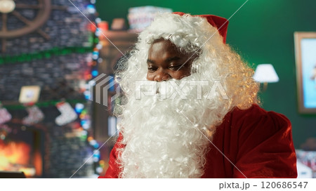 Black Santa discussing with parents around the world on online conference before Christmas eve, finding out about kids wishes for toys to bring the perfect gift. Saint Nick during holiday. Camera A. 120686547