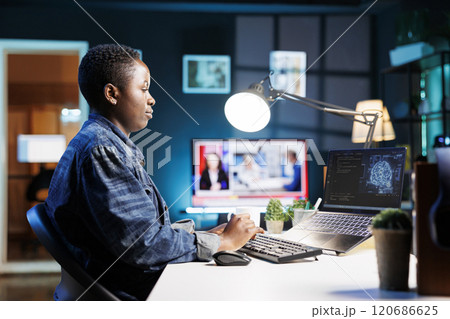 African American woman at desk using personal computer for programming and data analysis. Female freelancer in working at home, efficiently manages information technology and data center on laptop. African American woman at desk using personal computer for programming and data analysis. Female freelancer in working at home, efficiently manages information technology and data center on laptop. 120686625
