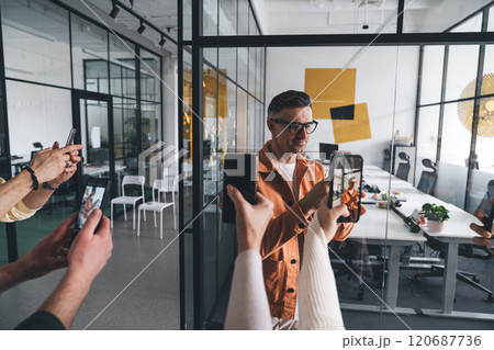 Unrecognizable people taking photo of man in modern workspace Unrecognizable people taking photo of man in modern workspace 120687736