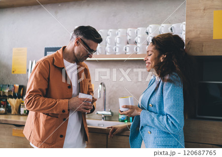 Smiling diverse couple with coffee in kitchen Smiling diverse couple with coffee in kitchen 120687765