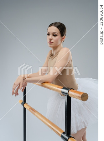 Ballet dancer practicing gracefully at the barre in a studio setting Ballet dancer practicing gracefully at the barre in a studio setting 120691654