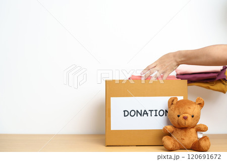 Kid Donation, Charity, Volunteer, Giving and Delivery Concept. Hand holding Bear doll and Clothes into Donation box at home for support and help poor, refugee and homeless people. Copy space for text Kid Donation, Charity, Volunteer, Giving and Delivery Concept. Hand holding Bear doll and Clothes into Donation box at home for support and help poor, refugee and homeless people. Copy space for text 120691672