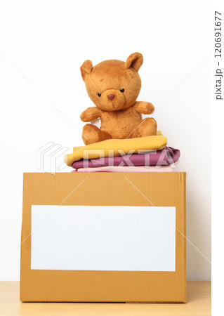 Kid Donation, Charity, Volunteer, Giving and Delivery Concept. Hand donate Bear doll and Clothes into cardboard box at home for support and help poor, refugee and homeless people. Copy space for text Kid Donation, Charity, Volunteer, Giving and Delivery Concept. Hand donate Bear doll and Clothes into cardboard box at home for support and help poor, refugee and homeless people. Copy space for text 120691677