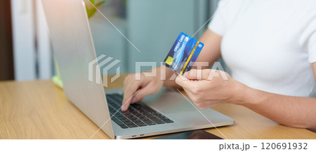 woman hand holding credit card and using laptop with mobile phone for online shopping while making order. Marketplace platform website, technology, ecommerce, digital banking and online payment woman hand holding credit card and using laptop with mobile phone for online shopping while making order. Marketplace platform website, technology, ecommerce, digital banking and online payment 120691932