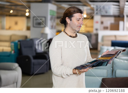 Man deciding on material for couch in furniture store 120692188