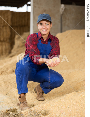Smiling female farmer with handful of soybean husk feed in her hands 120692445