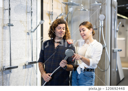 in plumbing department,man and woman examine shower head and quality of metal coating. in plumbing department,man and woman examine shower head and quality of metal coating. 120692448