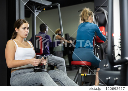 Caucasian woman doing exercises on cable row machine in gym 120692627