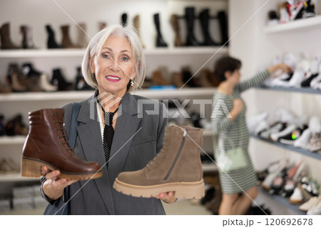 Mature woman takes samples from showcase and examines shoes 120692678