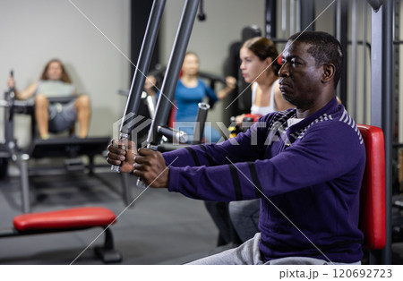 African man doing exercises on chest fly machine in gym African man doing exercises on chest fly machine in gym 120692723