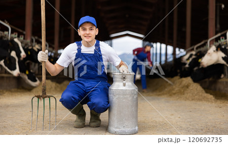 Farmer holding can and rake at cow farm 120692735