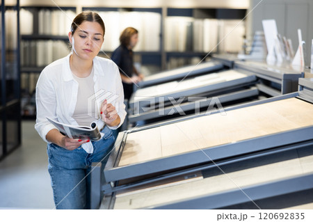 Focused woman choosing wall tiling materials in hardware shop Focused woman choosing wall tiling materials in hardware shop 120692835