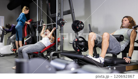 Men and women training on machines in gym 120692867