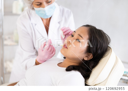 Middle-aged doctor giving injection in face Middle-aged doctor giving injection in face 120692955
