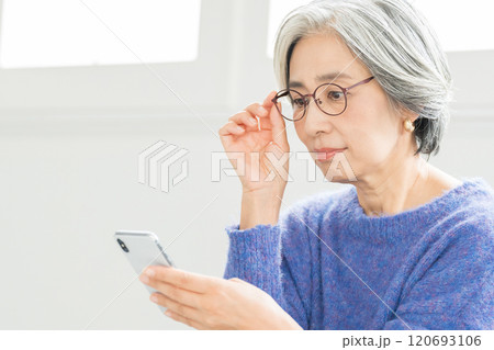 老眼鏡でスマホを見るシニア女性 老眼鏡でスマホを見るシニア女性 120693106