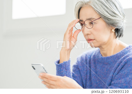 老眼鏡でスマホを見るシニア女性 老眼鏡でスマホを見るシニア女性 120693110