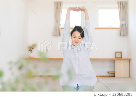 リビングで伸びをする女性 120693293