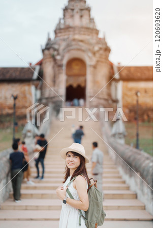 Young asian woman traveler in white dress with hat and bag traveling in Wat Phra That Lampang Luang, Tourist visit at Lampang, Thailand.. Asia Travel, Vacation and summer holiday concept 120693620