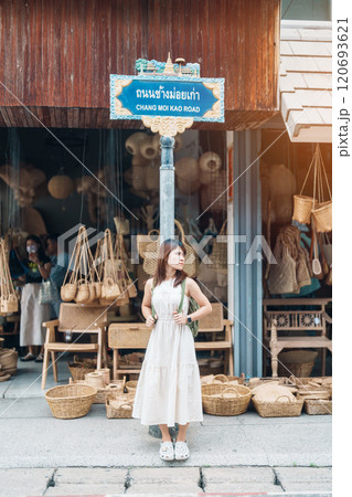 Young asian woman traveler in dress with hat traveling to wicker shop on Chang Moi Kao Road, Tourist visit at the old city in Chang Mai, Thailand. Asia Travel, Vacation and summer holiday concept Young asian woman traveler in dress with hat traveling to wicker shop on Chang Moi Kao Road, Tourist visit at the old city in Chang Mai, Thailand. Asia Travel, Vacation and summer holiday concept 120693621