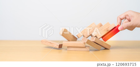 woman hand pulling wood domino blocks on table. Crisis, fall Business, Risk management, Economic recession, Strategy and solutions concept 120693715