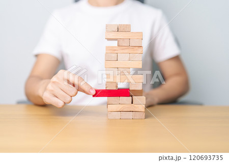 hand pulling wooden block tower on table. Business planning, Risk Management, Solution, leader, strategy, Crisis, falling Business, and Economic recession concept hand pulling wooden block tower on table. Business planning, Risk Management, Solution, leader, strategy, Crisis, falling Business, and Economic recession concept 120693735