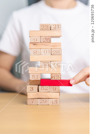 hand pulling wooden block tower on table. Business planning, Risk Management, Solution, leader, strategy, Crisis, falling Business, and Economic recession concept hand pulling wooden block tower on table. Business planning, Risk Management, Solution, leader, strategy, Crisis, falling Business, and Economic recession concept 120693736