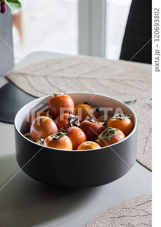 Beautiful Fresh Persimmons Arranged Elegantly in a Stylish Bowl on a Table for Display Beautiful Fresh Persimmons Arranged Elegantly in a Stylish Bowl on a Table for Display 120693802