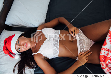 woman in lingerie on bed near christmas tree with gifts woman in lingerie on bed near christmas tree with gifts 120697469