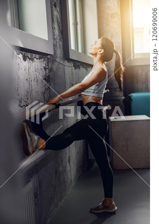A Young Woman Engaged in a Dynamic Stretching Routine in a StateoftheArt Gym Environment 120699006