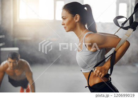 Engaging in Dynamic Fitness Training using Suspension Equipment inside a Workout Studio Engaging in Dynamic Fitness Training using Suspension Equipment inside a Workout Studio 120699019