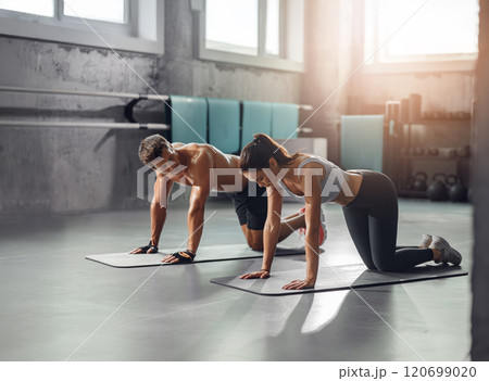A couple is engaging in a dynamic fitness workout together in a modern gym environment 120699020
