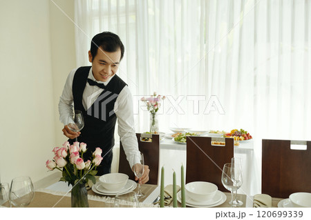 Smiling Waiter Preparing Elegant Dining Table Setup 120699339