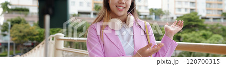 Smiling Woman Gesturing Outdoors with Headphones 120700315