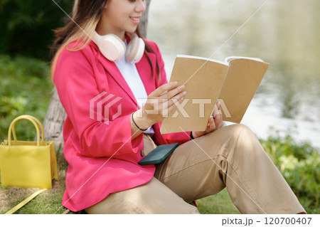 Woman Reading Book Outdoors in Green Park 120700407