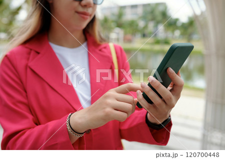Young Woman Wearing Red Blazer Using Smartphone Outdoors 120700448