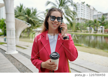 Smiling Woman Holding Coffee Wearing Pink Blazer Outdoors 120700450