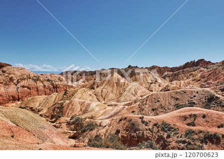 Vast landscape of colorful hills under a clear sky in a serene desert setting 120700623