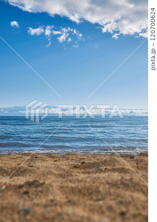 Sandy beach, Issyk-Kul Lake, Mountains in clouds, Sun rays, summer Kyrgyzstan 120700624